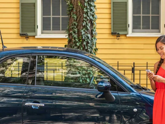 Woman reading phone outside blue fiat