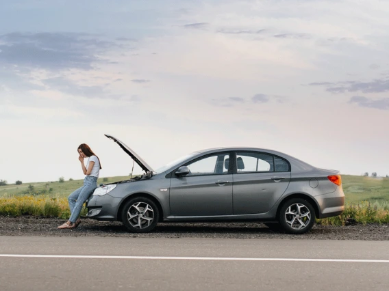 Woman standing by a broken down car