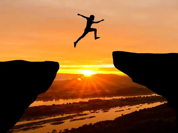 Man jumping across gap at sunrise