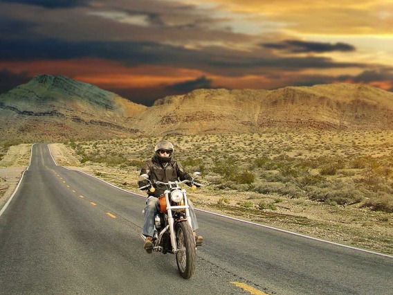 Motorcycle rider cruising through the desert at sunset